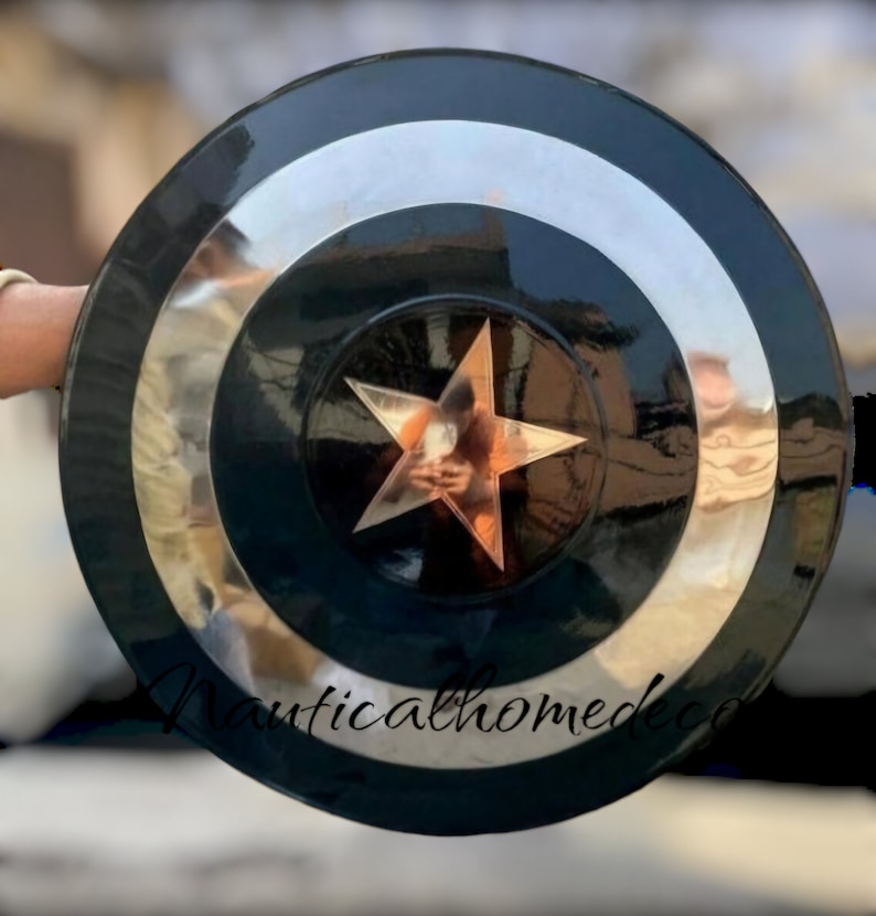 May include: A black and silver Captain America shield with a large, five-pointed star in the centre. The shield is made of metal and has a shiny finish.
