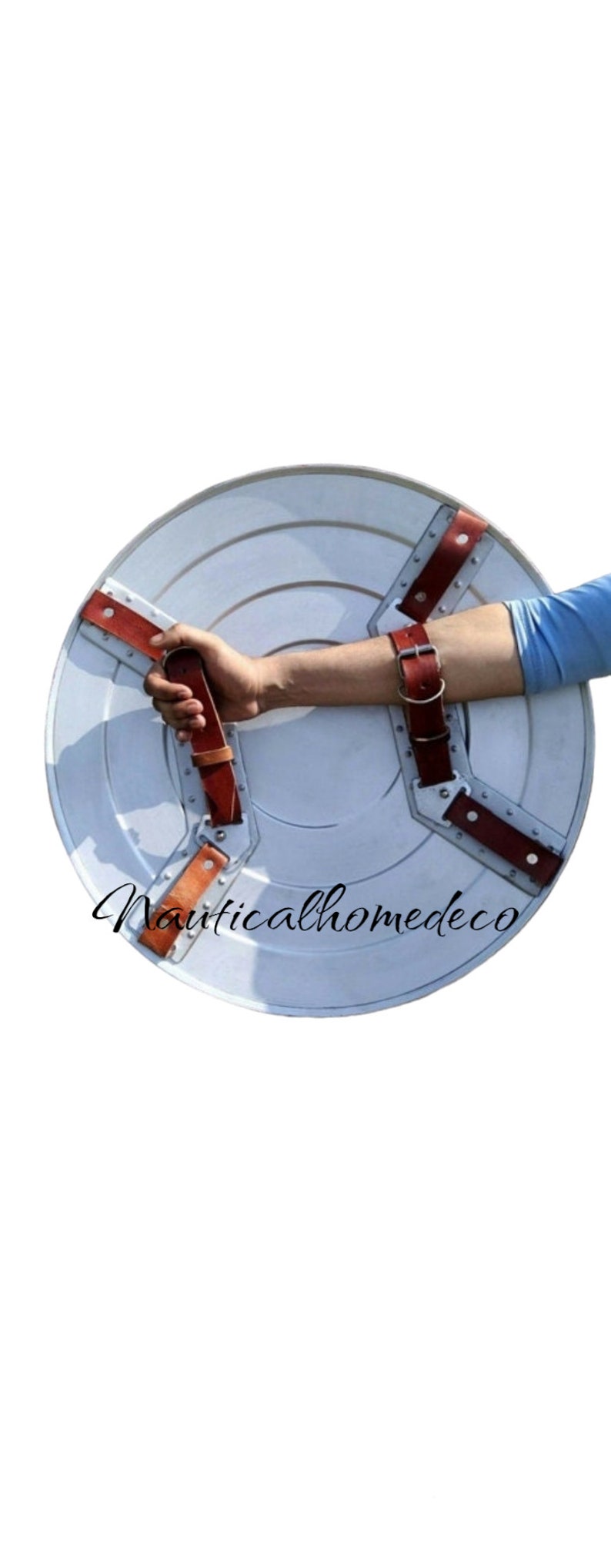 May include: A white metal shield with a red star in the centre. The shield has three brown leather straps with metal buckles. The shield is being held by a person's arm.