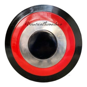 K&ouml;nnte beinhalten: Ein runder, schwarz-rot-silberner Schild mit konzentrischem Kreisdesign. Der Schild hat einen schwarzen Mittelkreis, einen silbernen Ring darum, einen roten Ring darum und einen schwarzen Ring um den gesamten Schild.