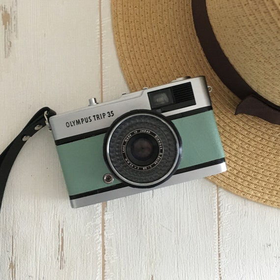 Old Film SLR Camera in a Worn Case, 35mm Film Reel, Lens Cap, Top