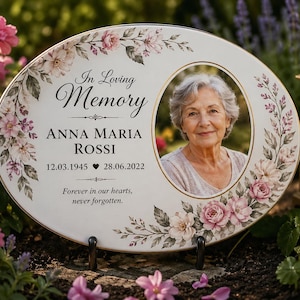 Puede incluir: Placa conmemorativa ovalada con una foto de una mujer, rodeada por un diseño floral en rosa y crema. La placa dice "In Loving Memory" e incluye el nombre "ANNA MARIA ROSSI" y fechas. También está presente el texto "Forever in our hearts, never forgotten".
