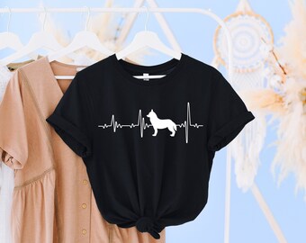 May include: Black t-shirt with a white silhouette of a dog with a heartbeat line above it. The shirt is hanging on a white hanger.