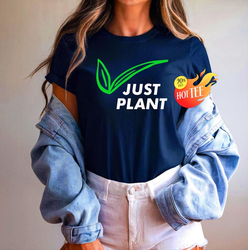 May include: Navy blue t-shirt with the text "JUST PLANT" in white, accompanied by a green leaf and checkmark design. A red and yellow sticker with the text "20% off HOT TEE" is on the right side.