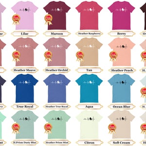 May include: A collection of t-shirts in various colors featuring a white silhouette of a poodle with a heartbeat line. The text "Best Poodle Ever" is printed on a gold circle sticker on each shirt.