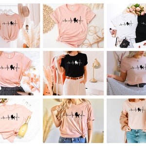 May include: A collection of six t-shirts featuring a poodle silhouette with a heartbeat line. The shirts are available in pink and black.