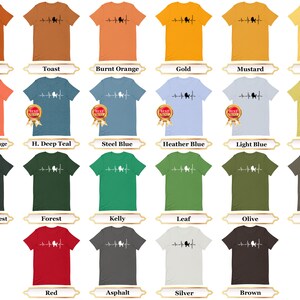 May include: A collection of t-shirts in various colors featuring a black silhouette of a poodle with a heartbeat line. The t-shirts are displayed on a white background.