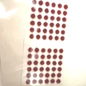 May include: Two rectangular sheets of paper with a grid of small, evenly spaced, maroon-colored dots. The dots are arranged in a pattern, creating a visual texture against the white background. The sheets are slightly transparent.