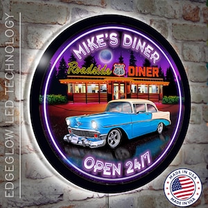 May include: A round, neon sign with a purple glow, depicting a vintage diner with a classic car parked in front. The sign reads "Mike's Diner" and "Roadside Diner" with the text "Open 24/7" at the bottom. The sign is made in the USA.
