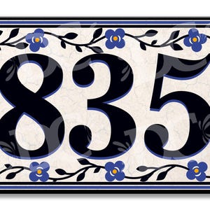 Pode incluir: Uma placa retangular de número de casa com os dígitos pretos 835 centralizados num fundo cor de creme com textura rachada. A borda é decorada com um padrão de flores azuis e vinhas pretas, envolvida por uma fina moldura azul.