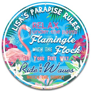 May include: A round, blue and white sign with a pink flamingo and tropical plants. The sign says "Lisa's Paradise Rules: Relax under the palms, Flamingle with the Flock, Get your feet wet, Ride the Waves, Watch the Sunset."