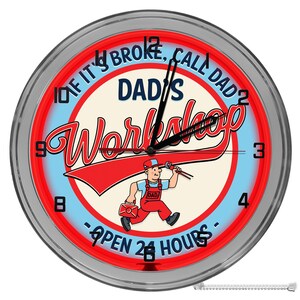 May include: A silver framed clock with a red and blue neon sign that says "If it's broke, call Dad. Dad's Workshop - Open 24 Hours" with a cartoon illustration of a man in overalls holding a wrench.