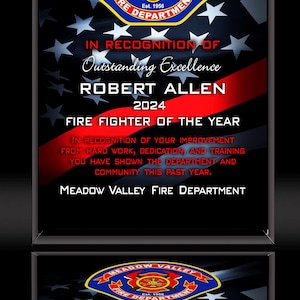 K&ouml;nnte beinhalten: Eine gerahmte Auszeichnung f&uuml;r Robert Allen, Feuerwehrmann des Jahres 2024, von der Meadow Valley Feuerwehr. Die Auszeichnung zeigt das Emblem der Abteilung, Text auf dem Hintergrund der amerikanischen Flagge und einen roten Streifen.