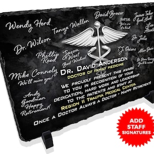 May include: A black slate plaque with a silver medical symbol and the text "DR. DAVID ANDERSON DOCTOR OF FAMILY MEDICINE" and "ONCE A DOCTOR ALWAYS A DOCTOR - HAPPY RETIREMENT!"  The plaque has a red star sticker with the text "ADD STAFF SIGNATURES".