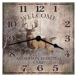 May include: A rustic wooden clock with a deer silhouette and the words "Welcome" and "Anderson Hunting Camp". The clock face has Roman numerals and black hands.
