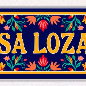 Può includere: Un cartello in ceramica blu e giallo con un motivo floreale e il testo "CASA LOZANO".