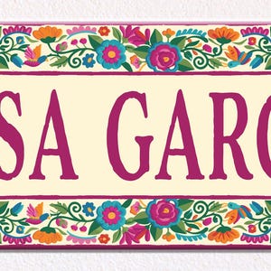 May include: A rectangular wall sign with a cream-colored center featuring the text CASA GARCIA in bold magenta letters. The sign is framed by a vibrant border of colorful painted flowers and green leaves in shades of blue, orange, and pink.