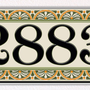 May include: Rectangular address plaque with the number 2883 in black, centered on a cream-colored background. The plaque is framed with a decorative border featuring green, orange, and cream-colored floral patterns. The plaque is mounted on a white surface.