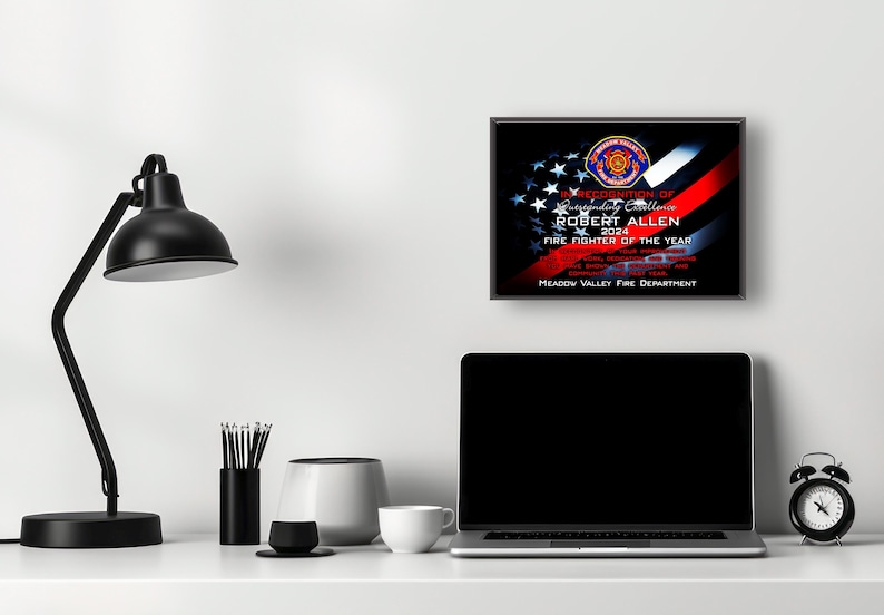K&ouml;nnte beinhalten: Eine gerahmte Auszeichnung f&uuml;r Robert Allen, Feuerwehrmann des Jahres 2024, von der Meadow Valley Fire Department. Die Auszeichnung zeigt ein Design mit der amerikanischen Flagge, einem roten Streifen und dem Emblem der Feuerwehr.