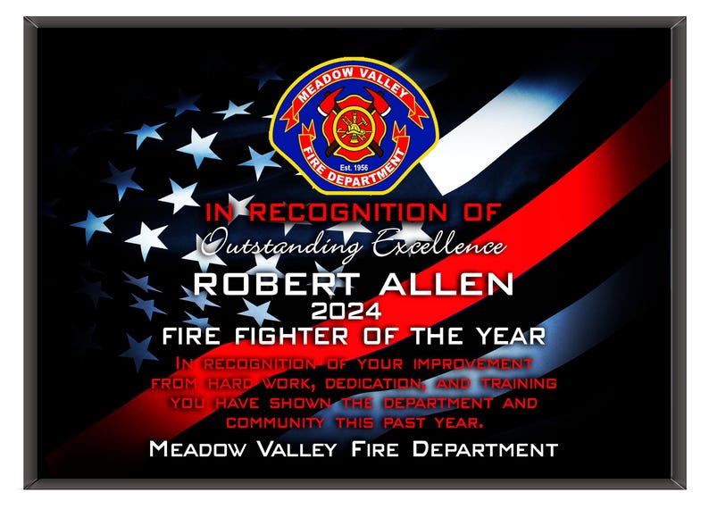 K&ouml;nnte beinhalten: Gerahmte Plakette mit schwarzem Rand, mit einem Design der amerikanischen Flagge und einem roten Streifen. Der Text lautet "IN ANERKENNUNG AUSSERGEW&Ouml;HNLICHER EXZELLENZ ROBERT ALLEN 2024 FEUERWEHRMANN DES JAHRES". Das Logo der Meadow Valley Feuerwehr befindet sich oben.
