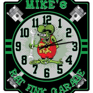 May include: A black and green wall clock with the text "Mike's Rat Fink Garage." The clock face features a cartoon rat holding a wrench. The clock has four piston graphics and green accents.