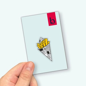 Puede incluir: Una tarjeta blanca con una "b" roja en la esquina superior derecha. Una ilustración en blanco y negro de un cono de papel lleno de patatas fritas amarillas se encuentra en el centro de la tarjeta.
