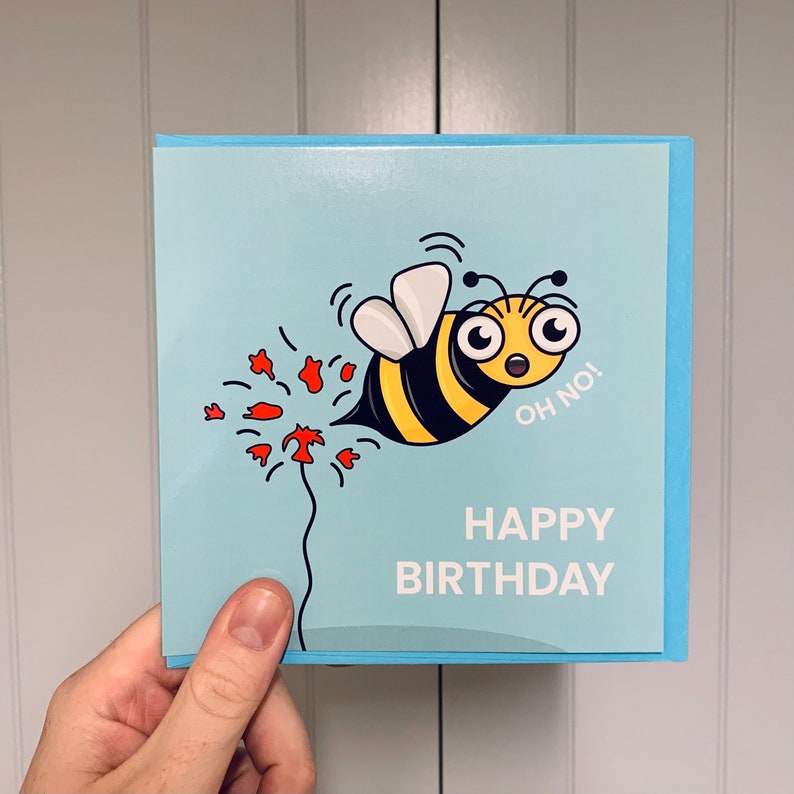 May include: A blue birthday card with a cartoon bee flying away from a red flower with the text "Oh no!" and "Happy Birthday".