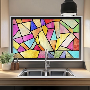 May include: A colourful stained glass window film with geometric shapes in shades of pink, blue, yellow, green, and orange. The film is applied to a window above a kitchen sink.