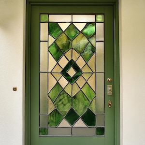 May include: A green wooden door with a stained glass window featuring a geometric pattern of green and beige diamond shapes.