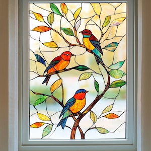 Puede incluir: Una ventana de vitral con un árbol colorido con tres pájaros. Los pájaros son rojos, naranjas, azules y amarillos. El árbol tiene hojas y ramas verdes.