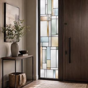 Puede incluir: Una puerta rectangular alta con un panel de vidrio tintado con un patrón de cuadrícula geométrica en tonos blanco, azul pálido, dorado y verde. La puerta es de madera oscura e incluye un mango vertical largo de metal negro y una cerradura.