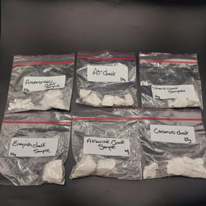 Op de afbeelding: Zes doorzichtige plastic zakjes met witte krijtmonsters. Elk zakje heeft een label met het type krijt en het gewicht in gram. De soorten krijt zijn: Artemovoktik krijtmonster, luchtkrijt, scherf krijtmonsters, Engels krijtmonster, Akbulak krijtmonster en kokoskrijt.