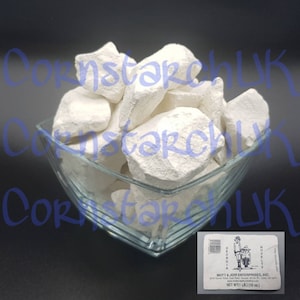 May include: A glass bowl filled with white chalk rocks. The label on the front of the bowl reads "Mutt & Jeff Enterprises, Inc. Georgia Novelty 2010 Bowman Road, East Point, Georgia 30344 Phone: 404-761-0413 Net Wt (1 lb) (16 oz)"