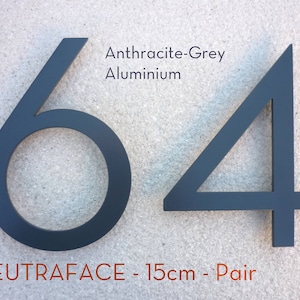Peut inclure: Une paire de numéros de maison modernes noirs de 15 cm, 6 et 4, en aluminium anthracite. Les numéros sont montés sur un mur texturé gris clair. Le texte "NEUTRAFACE - 15cm - Pair" est imprimé sous les numéros.