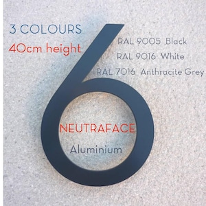 Könnte beinhalten: Eine schwarze Hausnummer sechs aus Aluminium in der Schriftart Neutraface mit 40cm Höhe. Text gibt 3 Farben an: RAL 9005 Schwarz, RAL 9016 Weiß, RAL 7016 Anthrazitgrau. Die Zahl ist vor einem strukturierten hellgrauen Hintergrund abgebildet.