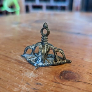 以下が含まれることがあります： 尖った頂上と装飾的な土台を持つ、小さな、装飾的なブロンズ色の金属製の装飾品。装飾品は、複雑な彫刻を施した詳細なデザインになっています。