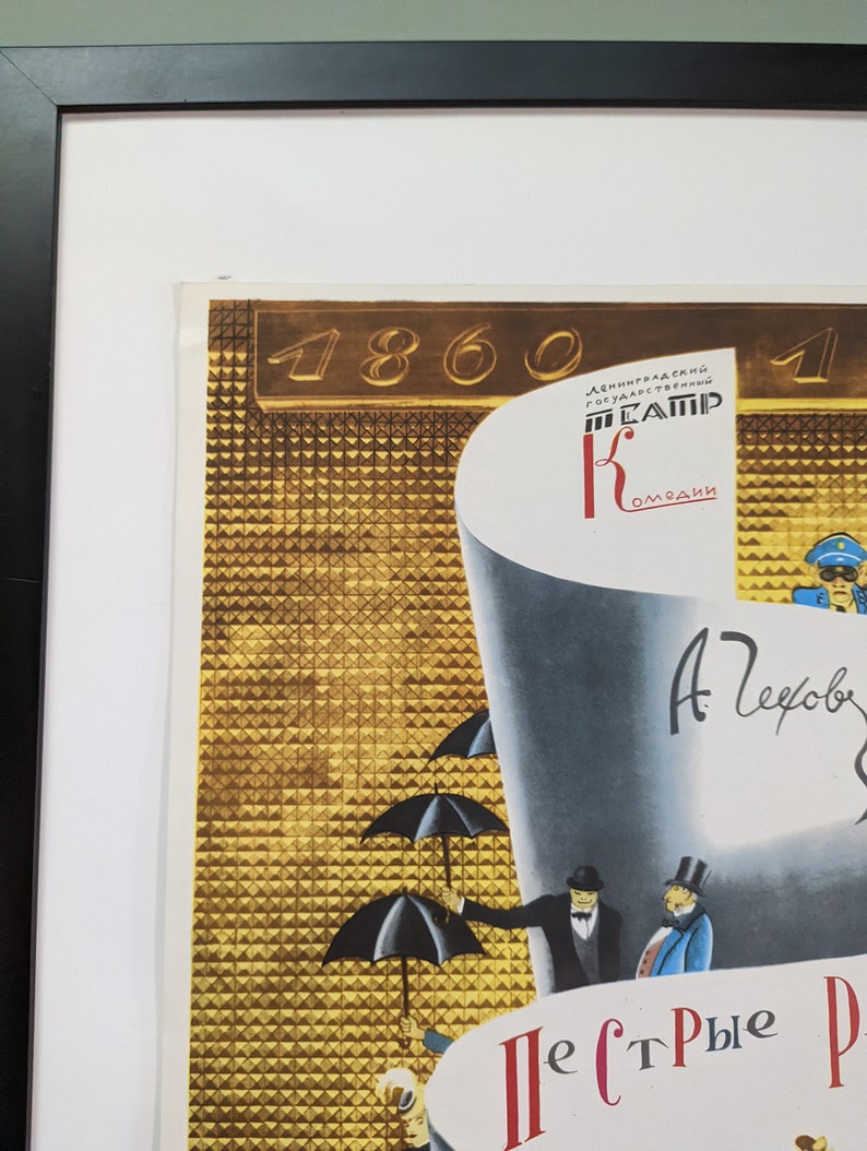 May include: Framed vintage poster with a black frame. The poster features a gold geometric background with the number 1860. The poster has illustrations of people with umbrellas and text in Russian.