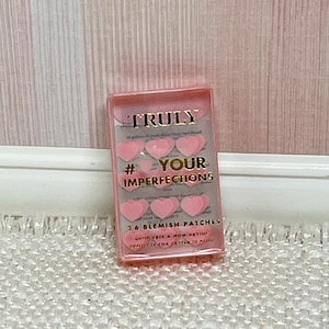 May include: A pink box of heart-shaped pimple patches with the text "TRULY #YOUR IMPERFECTIONS 36 BLEMISH PATCHES" on the front.