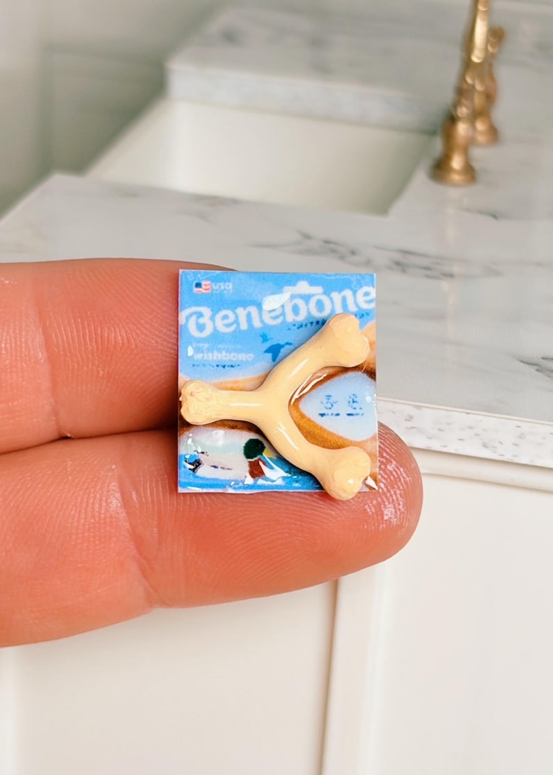 May include: Miniature Benebone wishbone dog chew toy on a blue package. The toy is a light tan colour and is shaped like a wishbone. The package has the Benebone logo and the word "wishbone" printed on it.