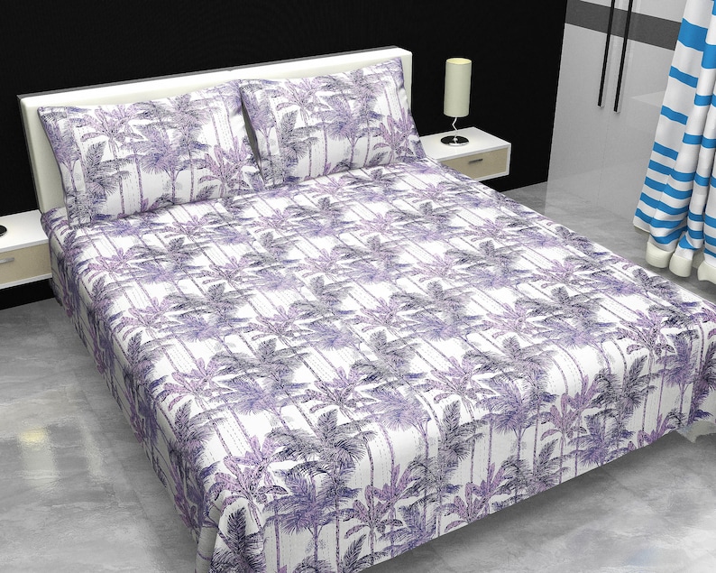 May include: A bed covered with a white sheet and pillowcases featuring a repeating pattern of purple palm trees. The bedding set includes two pillowcases and a fitted sheet. The room has a white headboard and a side table with a lamp.