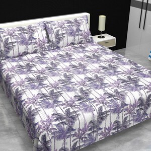 May include: A bed covered with a white sheet and pillowcases featuring a repeating pattern of purple palm trees. The bedding set includes two pillowcases and a fitted sheet. The room has a white headboard and a side table with a lamp.