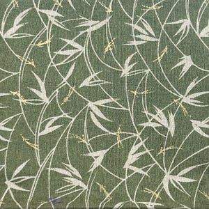May include: A dark green fabric featuring a repeating pattern of white bamboo stalks and leaves, accented with small, scattered gold-colored flecks. The material has a visible woven texture throughout, creating a consistent and detailed surface design.