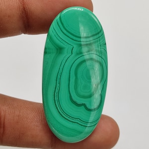 Peut inclure: Un cabochon de malachite vert en forme d'ovale avec un motif tourbillonnant.