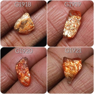May include: Four pieces of sunstone, each with a different shape and size. The stones are a mix of orange and gold colors with a shimmery, iridescent finish. The stones are labeled G1918, G1919, G1920, and G1921.