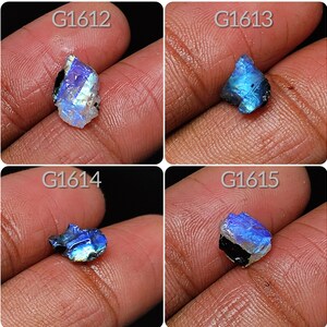 May include: Four iridescent blue labradorite gemstones with black inclusions. The stones are labeled G1612, G1613, G1614, and G1615.
