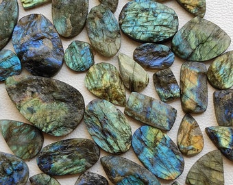 Könnte beinhalten: Eine Sammlung von schillernden Labradorit-Edelsteinen in verschiedenen Formen und Größen. Die Steine haben eine blaugrüne Farbe mit goldenen und silbernen Schimmern.