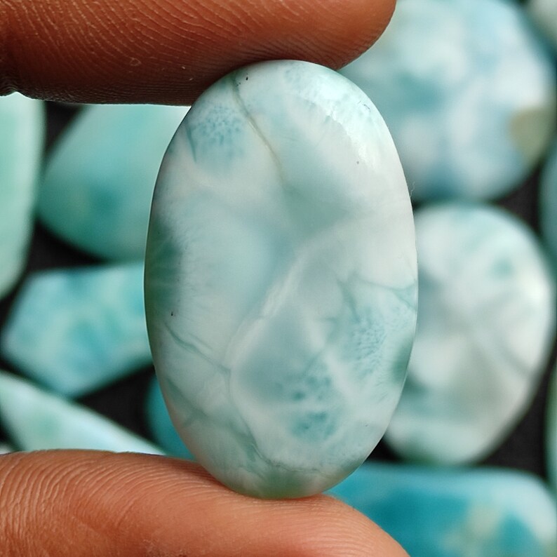 May include: Oval shaped cabochon of blue and white  cabochon with a cloudy, marbled pattern.