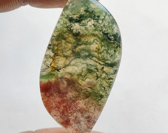 Op de afbeelding: Een groene, bruine en witte agaat cabochon met een uniek, wervelend patroon. De cabochon is geslepen in een traanvorm en heeft een glad, gepolijst oppervlak.