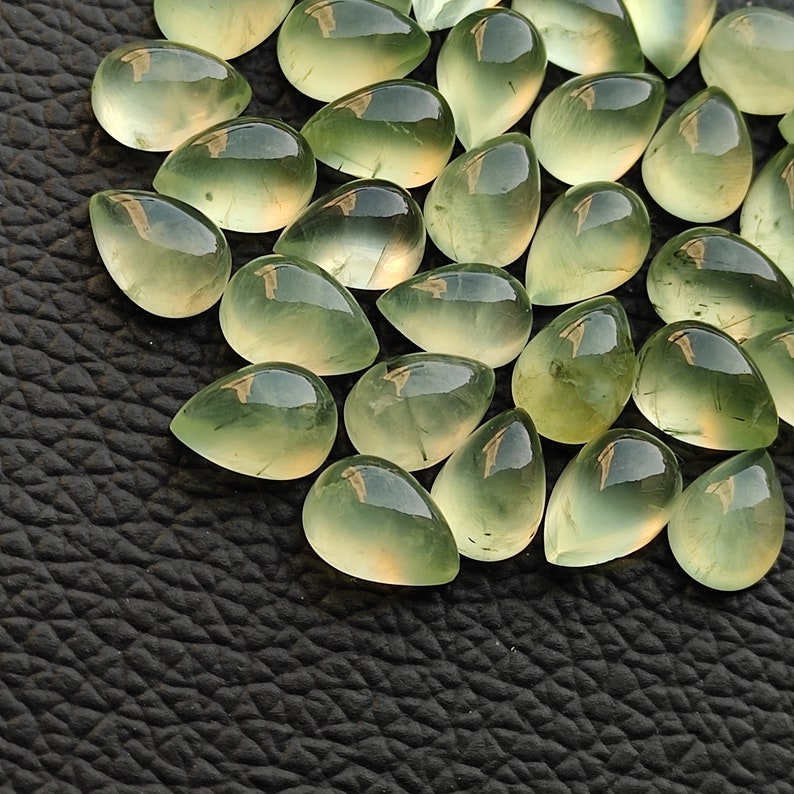May include: A collection of green teardrop-shaped gemstones, also known as aventurine, with a translucent, glassy finish.