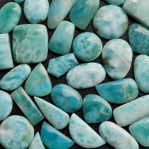 May include: A collection of various shapes and sizes of blue and white gemstone cabochons. The cabochons are smooth and polished, with a variety of patterns and textures.