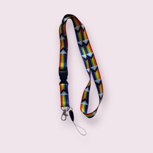 May include: A rainbow lanyard with a black clip and a silver swivel hook. The lanyard has a repeating pattern of rainbow triangles.